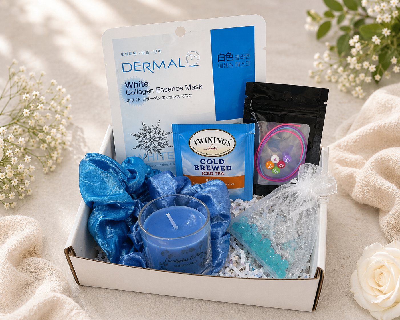 Gift box with blue candles, tea, and other items on a light background