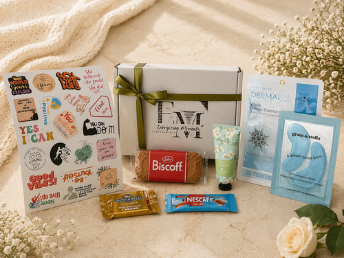 Assorted items including a box, snacks, and skincare products on a textured surface with flowers.