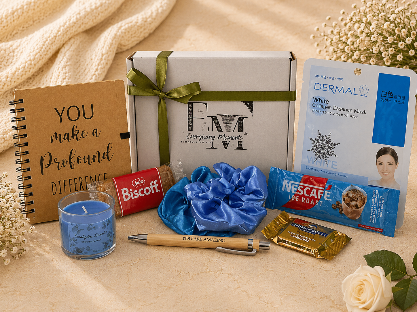 Gifting items including a notebook, candles, and snacks on a textured surface with flowers.