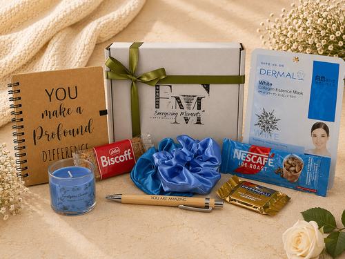 Gifting items including a notebook, candles, and snacks on a textured surface with flowers.