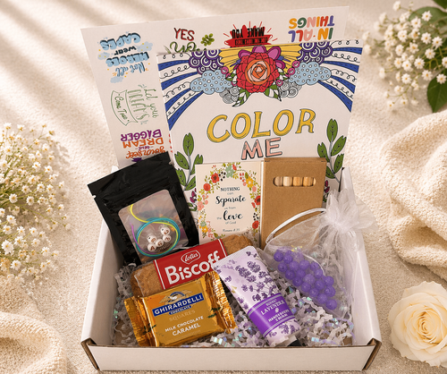 Gift box with 'Color Me' book, snacks, and decorative items on a soft background.