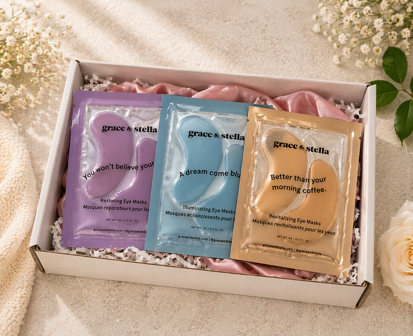 Three eye mask packets from grace & stella in a box with flowers in the background