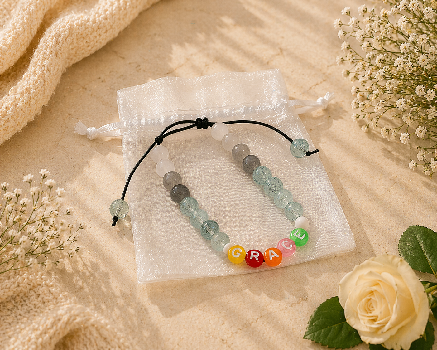 Bracelet with colorful beads spelling 'GRACE' on a beige surface with flowers.