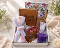 Gift box with a towel, notebook, and other items on a light background