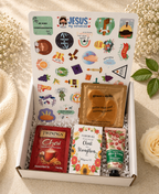 Gift box with various items including a tea bag, lotion, and stickers on a textured surface.