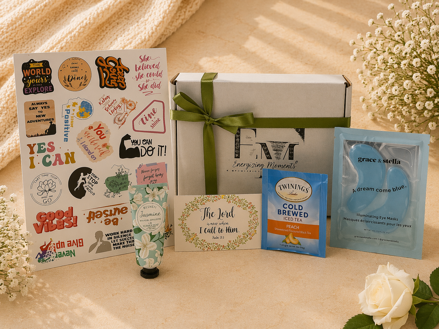 Collection of items including a box, stickers, hand cream, and eye masks on a light surface with flowers.