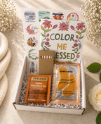 Gift box with tea, eye mask, and decorative items on a light background