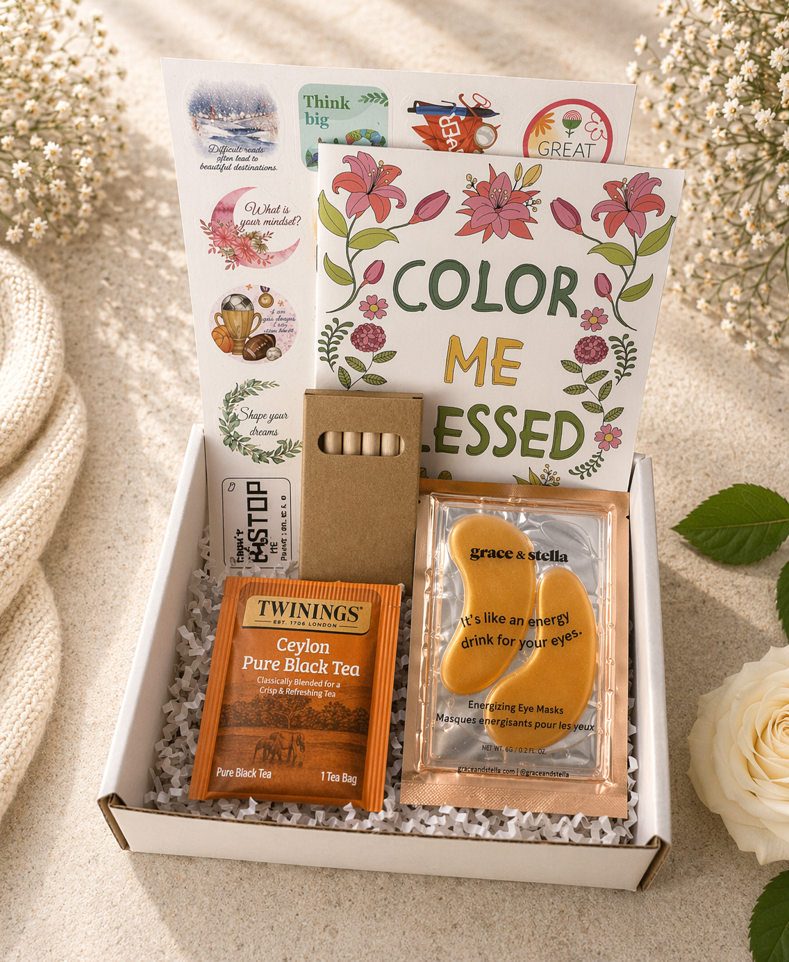 Gift box with tea, eye mask, and decorative items on a light background