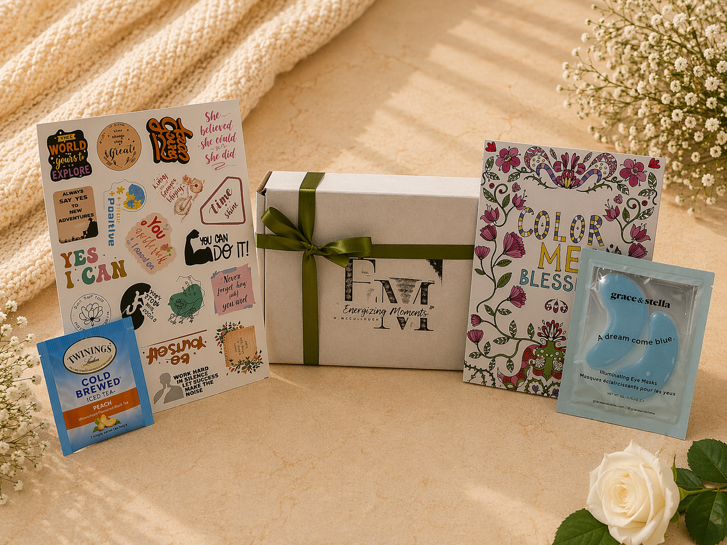 Gift box with decorative cards and a small packet on a textured surface with flowers.