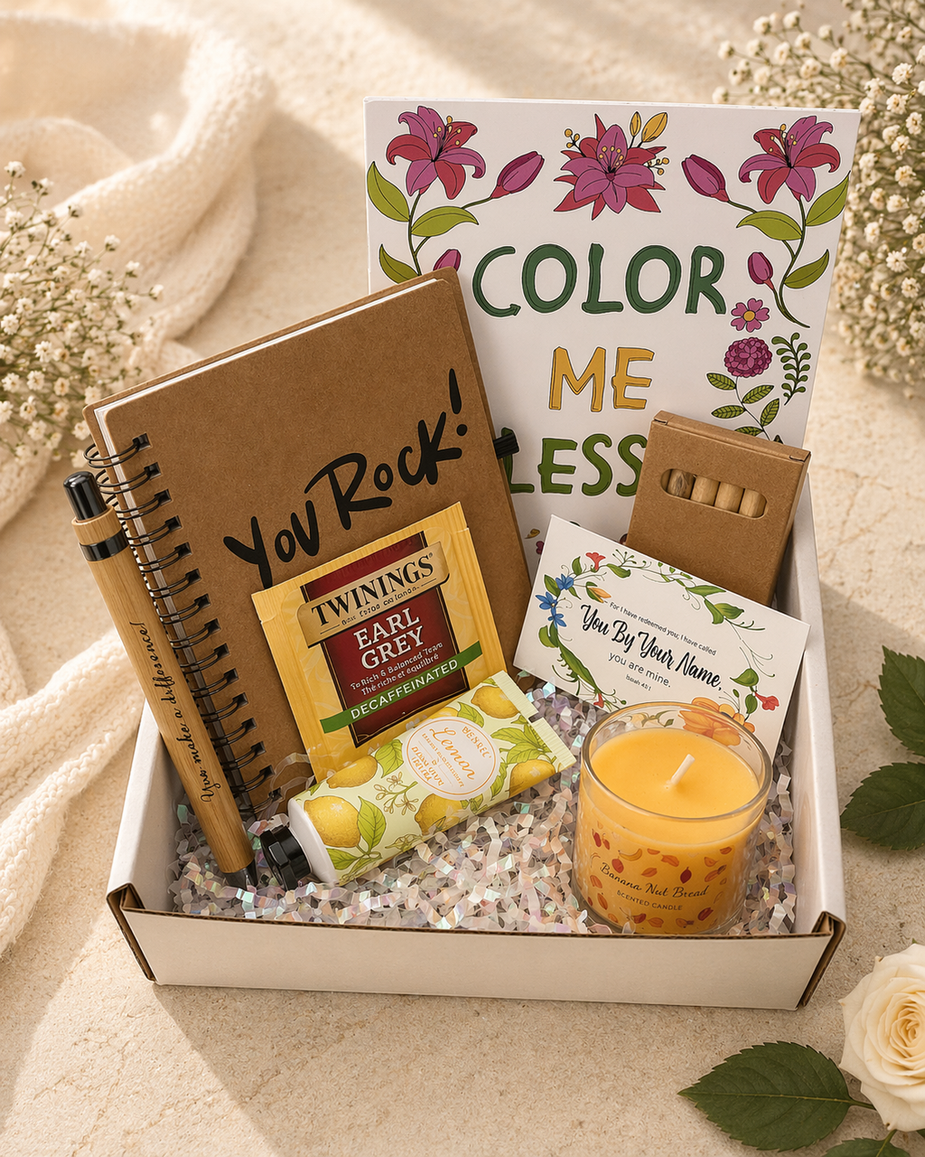 Gift box with stationery items, a candle, and a card on a soft surface.