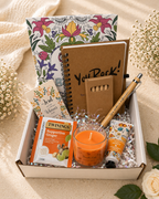 Gift box with a candle, notebook, and other items on a light background