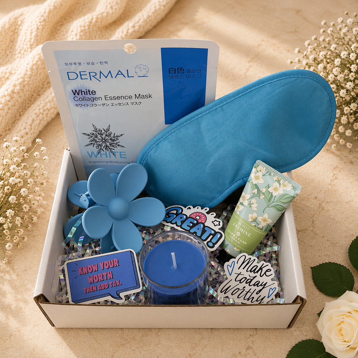 Gift box with blue eye mask, flower-shaped items, and motivational phrases on a beige background.